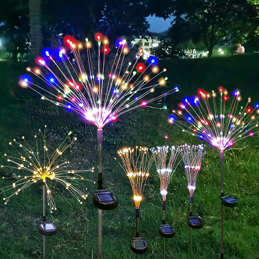 Solar firework stake lights glowing in a garden at night