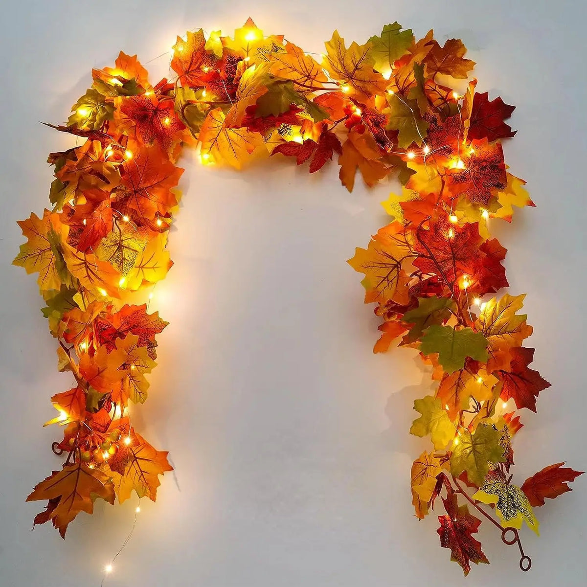 Artificial maple leaf garland with warm lights on a mantel